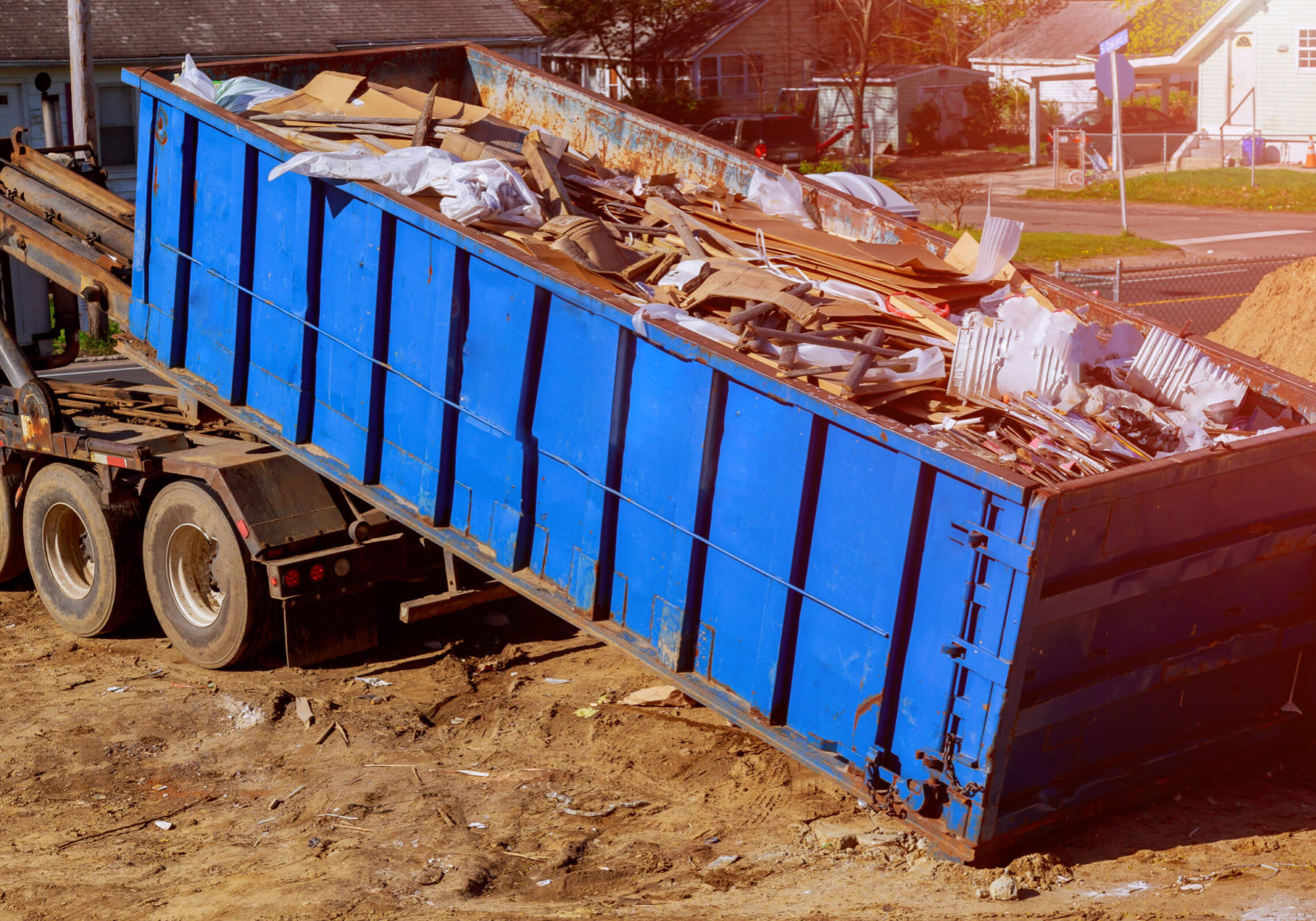 Industrial garbage bin blue construction debris container filled with rock and concrete rubble.